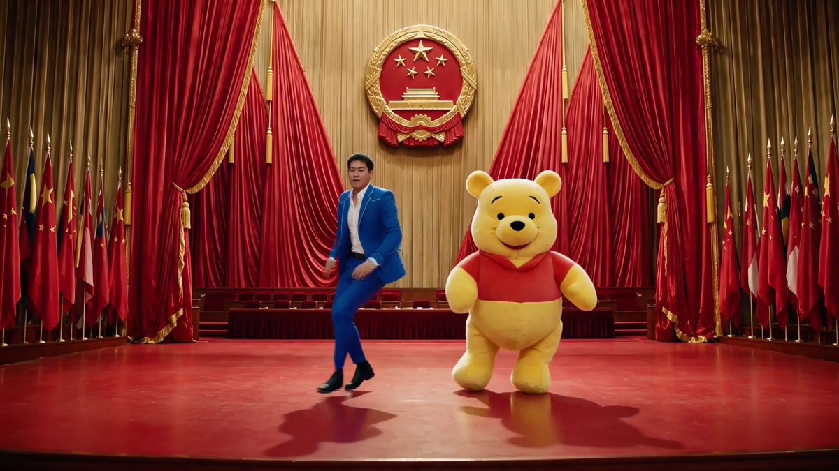 中国の国章と国旗を思わせる背景の赤い舞台で主人公と赤い服の黄色いクマが踊る