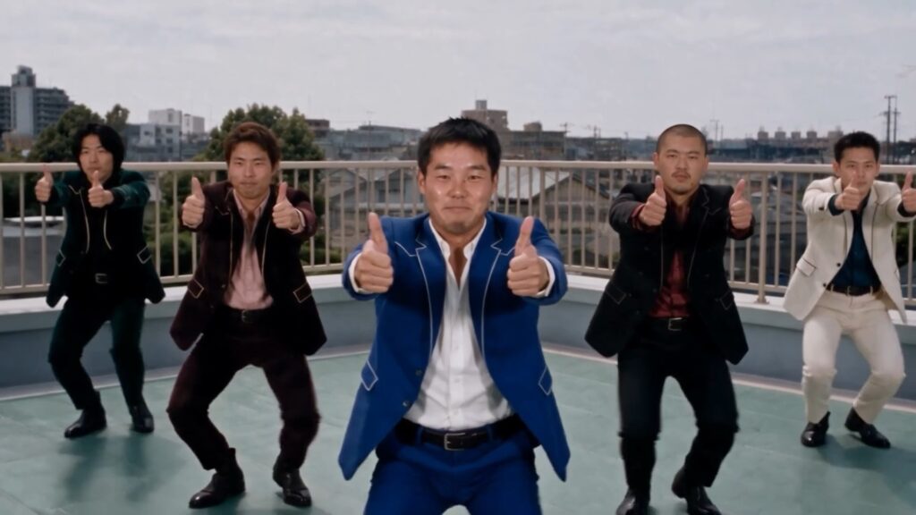 INMU KINGのMVで、屋上の手すりを背に野獣先輩・遠野・MUR・KMRなどのモチーフが踊る場面。